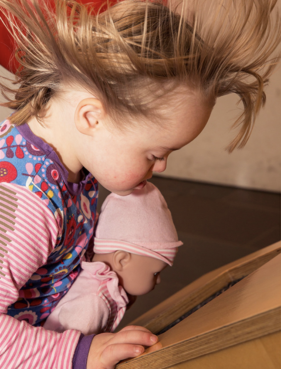 A young girl with Down Syndrome holding a doll